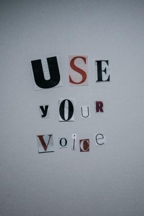 Auf dem Bild sind ausgeschnittene Buchstaben zu der englischen Aussage "Use your voice" zusammengesetzt. Das bedeutet: "Nutze deine Stimme".